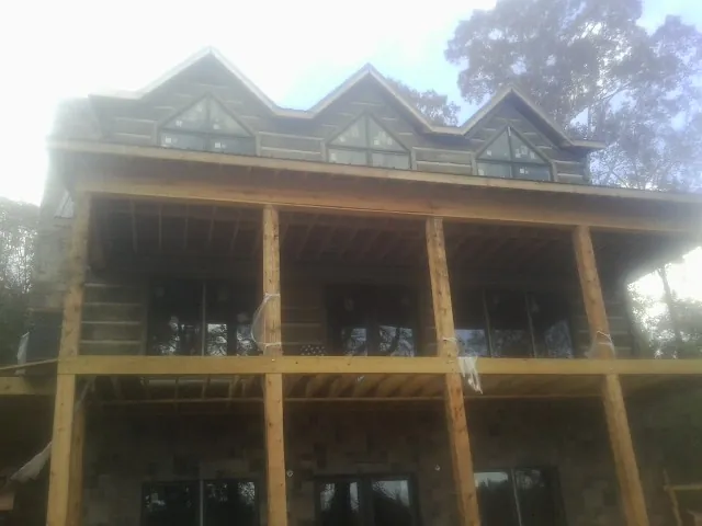 Dormers and porch framing on a large log home under construction — Roof Coating work by our crew in Somerville