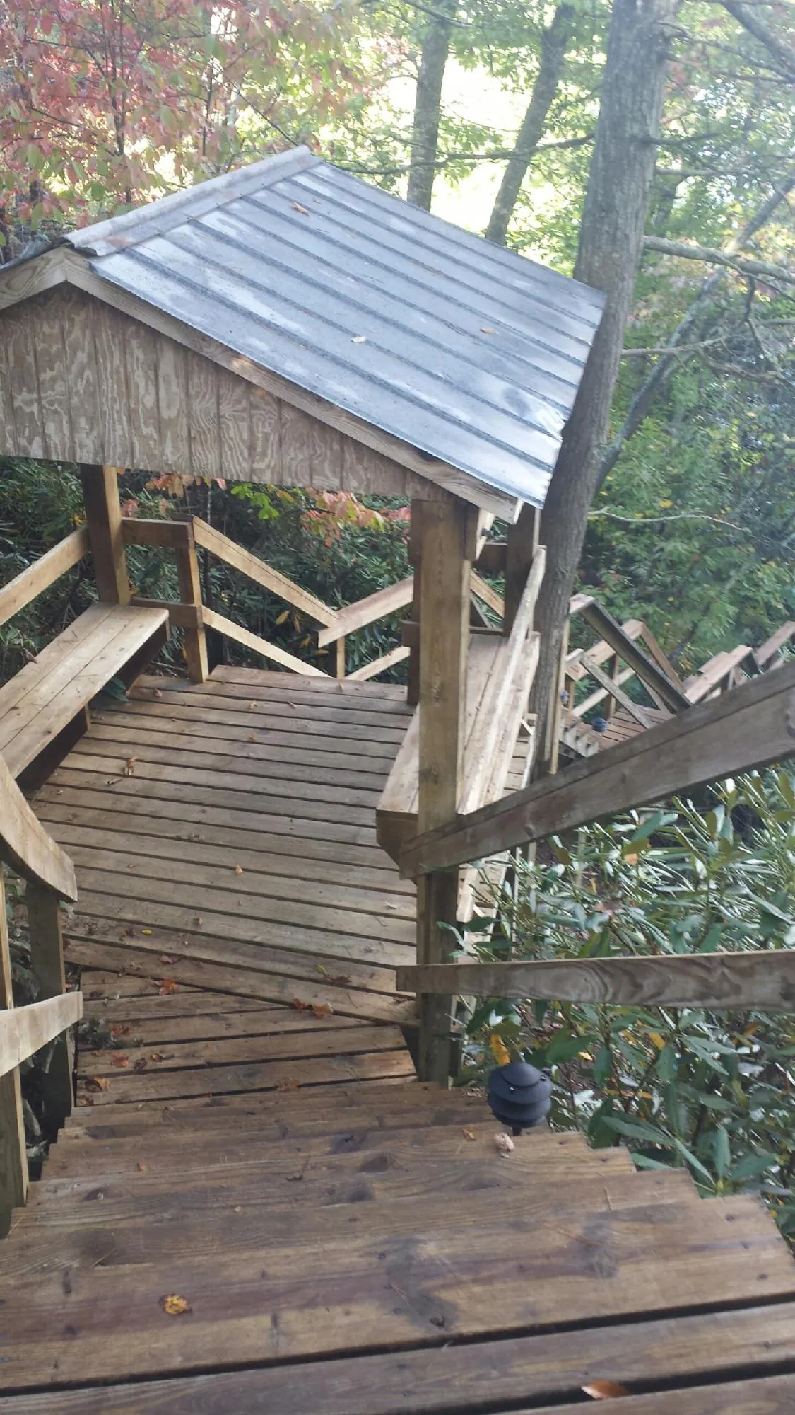 Metal roofed shelter over wooden steps on a wooded walkway — Skylight Repair & Installation work by our crew in Somerville