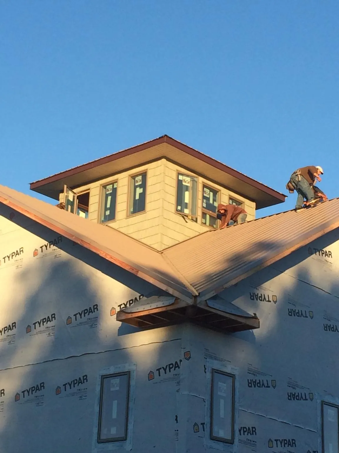 Roofers working around a rooftop cupola on a new metal roof at sunset — Roof Waterproofing in Somerville by Roofing Brothers